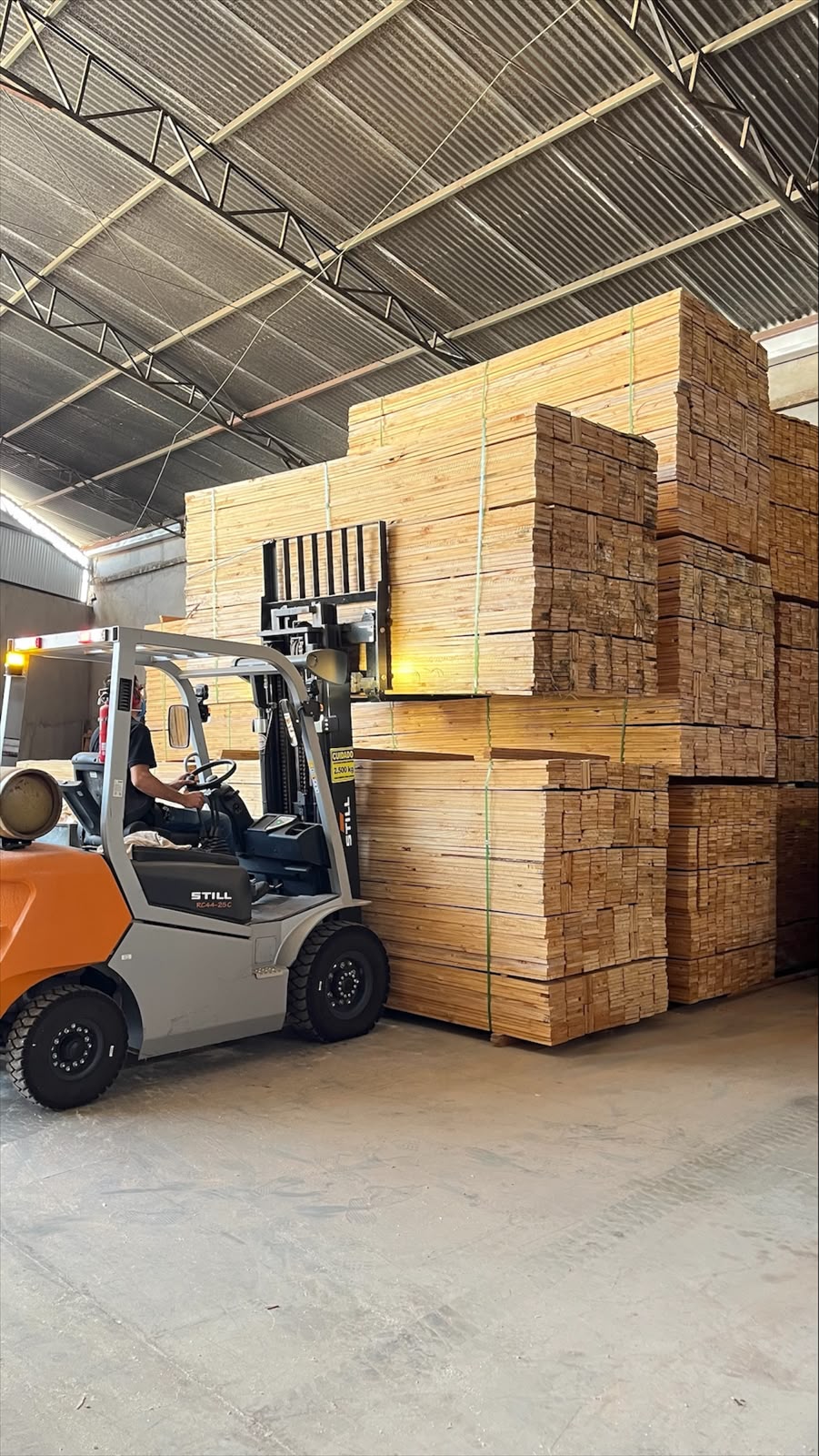 Empilhadeira transportando madeira selecionada no galpão da Madeferro